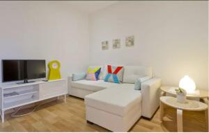 a living room with a white couch and a tv at Sea Apartament in Sant Adria de Besos