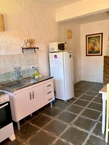 a kitchen with a white refrigerator and a sink at Chalés Bambá in Ilhabela