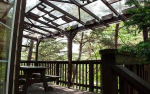 a wooden pergola with a picnic table on a deck at Goesan Jakeun Saejae Pension in Koesan