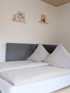 a white bed with two pictures on the wall at Blaues Häuschen an der Burg in Neuenstein