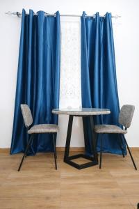 two chairs and a table in front of a blue curtain at Cj apartment kasoa in Kasoa