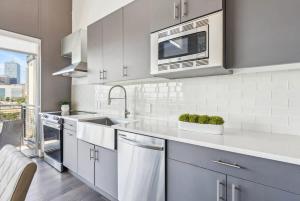 a white kitchen with a sink and a microwave at Penthouse Luxe Views No 604 in Dallas