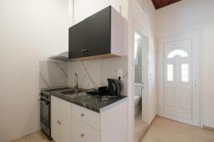 a white kitchen with a sink and a stove at Katsaros Studios & Apartments in Sidari