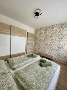 a bedroom with two beds and a wall with flowers at Green Nest Apartment in Sárvár