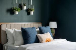 a bed with blue and white pillows and potted plants at Penthouse Dallas no 603 in Dallas