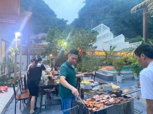 a man cooking food on a grill on a table at Tam Coc Harmony Homestay in Vũ Lâm