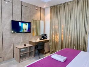 a bedroom with a bed and a desk and a tv at Purple Lavender Hotel Lekki in Lekki
