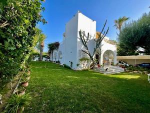 a white house with a yard with green grass at Villa Jasmin in Hammamet