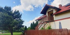 a house with a red roof and a wooden fence at Pokoje Gościnne Leśna 33 in Sława