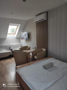 a bedroom with a bed and chairs and a window at Pokoje Gościnne Leśna 33 in Sława