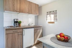 a kitchen with wooden cabinets and a bowl of apples at Alte Dorfstraße 29 REETungsring in Behrensdorf