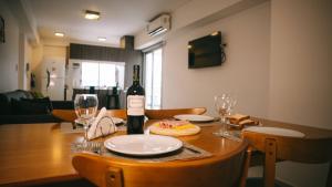 a table with a bottle of wine and glasses on it at HOMEFULL Apartamentos in Salta