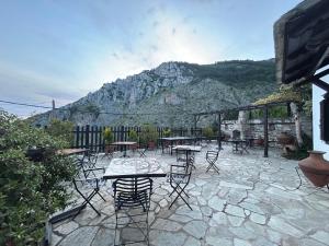 a patio with tables and chairs in front of a mountain at Hotel Adam in Makrinitsa