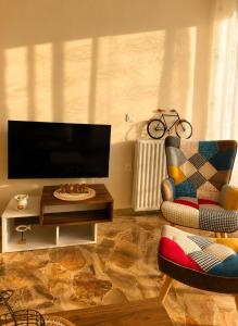 a living room with a tv and a chair and a table at MariosGuestHouse in Ancient Epidauros