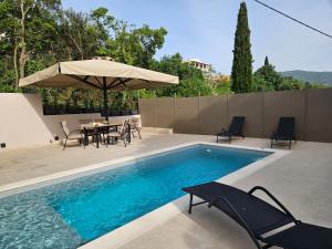 ein Pool mit Tisch, Stühlen und Sonnenschirm in der Unterkunft Casa Sofia in Dassia