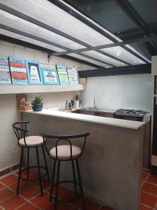 a kitchen with two bar stools and a sink at Hostal Casa Primavera in Medellín