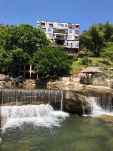 a waterfall in a pond with a building in the background at Eco hotel el molino in San Luis