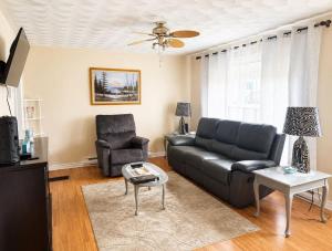 a living room with a black couch and a chair at Long Beach Lookout Vacation Rental in Twillingate