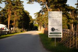 a sign on the side of a road next to a fence at Sandvikens Strandby in Katthammarsvik