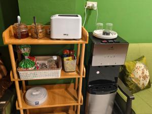 a kitchen with a coffee maker on a shelf next to a refrigerator at Happy Homey Hostel in Suratthani