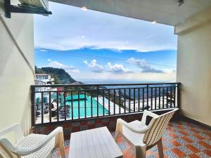 a balcony with chairs and a view of the ocean at Mokshada Hotel & Resort A Premium Property Near Jaypee in Mussoorie