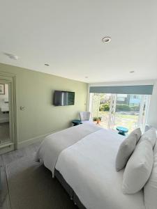 a bedroom with a large white bed and a window at Tŷ Treflan in Aberdyfi