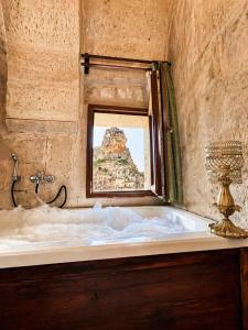a bath tub in a room with a window at Masar Cave Konak in Ortahisar +51 photos