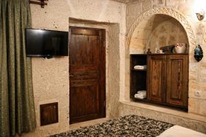a room with a tv on a stone wall at Masar Cave Konak in Ortahisar