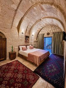 a bedroom with a large bed in a stone room at Masar Cave Konak in Ortahisar