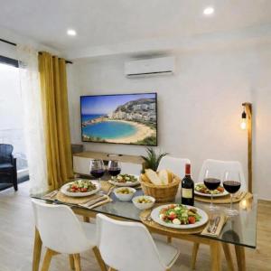 a dining room with a table with food and wine glasses at Deluxe Arguineguin Beach in Arguineguín