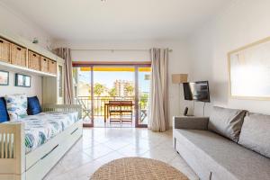 a bedroom with a bed and a couch and a balcony at Dunas de vilamoura in Quarteira