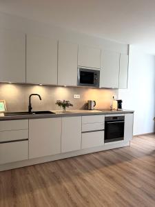 a kitchen with white cabinets and a sink at VIRIDIS Apartment in Františkovy Lázně