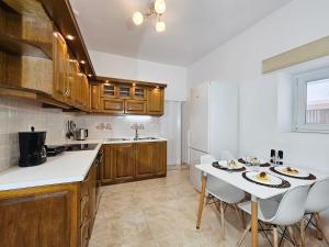 a kitchen with wooden cabinets and a white table with chairs at Casa Nevina in Marathokampos