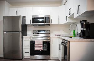 a kitchen with stainless steel appliances and white cabinets at Restful Basement Suite Hideaway in Saskatoon