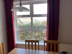 a dining room table and a window with a stone wall at Central Two Bed Apartment looking over the Harbour in Dunfanaghy +3 photos