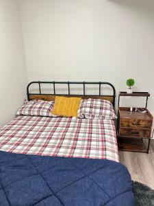 a bed with a plaid blanket and a night stand at Restful Basement Suite Hideaway in Saskatoon