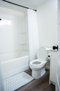 a white bathroom with a toilet and a bath tub at Restful Basement Suite Hideaway in Saskatoon +29 photos