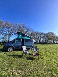a van parked in a field with two chairs and a table at Cranford Oak Farm Campsite in Barnstaple