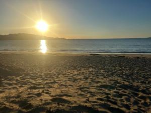 a beach with the sun rising over the ocean at Cranford Oak Farm Campsite in Barnstaple
