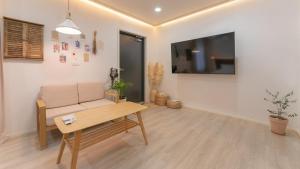 a living room with a couch and a tv on the wall at Yangyang Stay Wabom in Yangyang