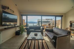 a living room with couches and a table and a large window at MINI LOFT Departamentos Bariloche in San Carlos de Bariloche