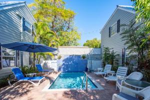 a swimming pool with chairs and an umbrella next to a house at Andros Suite in Key West