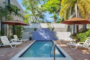 a swimming pool with chairs and umbrellas next to a building at Andros Suite in Key West