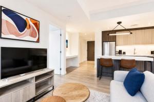 a living room with a large television and a kitchen at Luxury Seaport Stay Rooftop & Pool in Boston