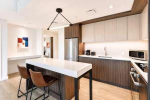 a kitchen with a white counter and chairs in it at Luxury Seaport Stay Rooftop & Pool in Boston