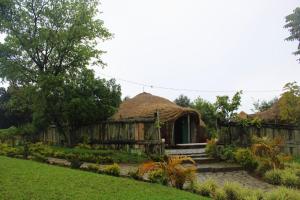 eine kleine Hütte mit Strohdach in einem Garten in der Unterkunft Kitabi EcoCenter in Kitabi