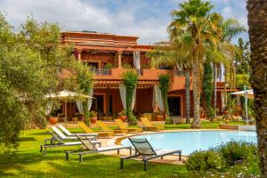 a resort with a pool and lounge chairs and palm trees at Mila Dyafa in Oulad Akkou