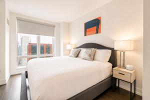 a bedroom with a large white bed with a window at Luxury Apt with Gym & Pool in New York +13 photos