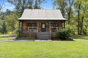 a log cabin with a metal roof on a grass field at A Rivers Edge in Mineral Bluff