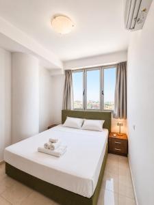 a bedroom with a large white bed with a window at TOP RATED - PREMIUM Seaview 2-BDR-Apt in tallest building in Larnaca - 2 min Walk to Beach in Larnaca